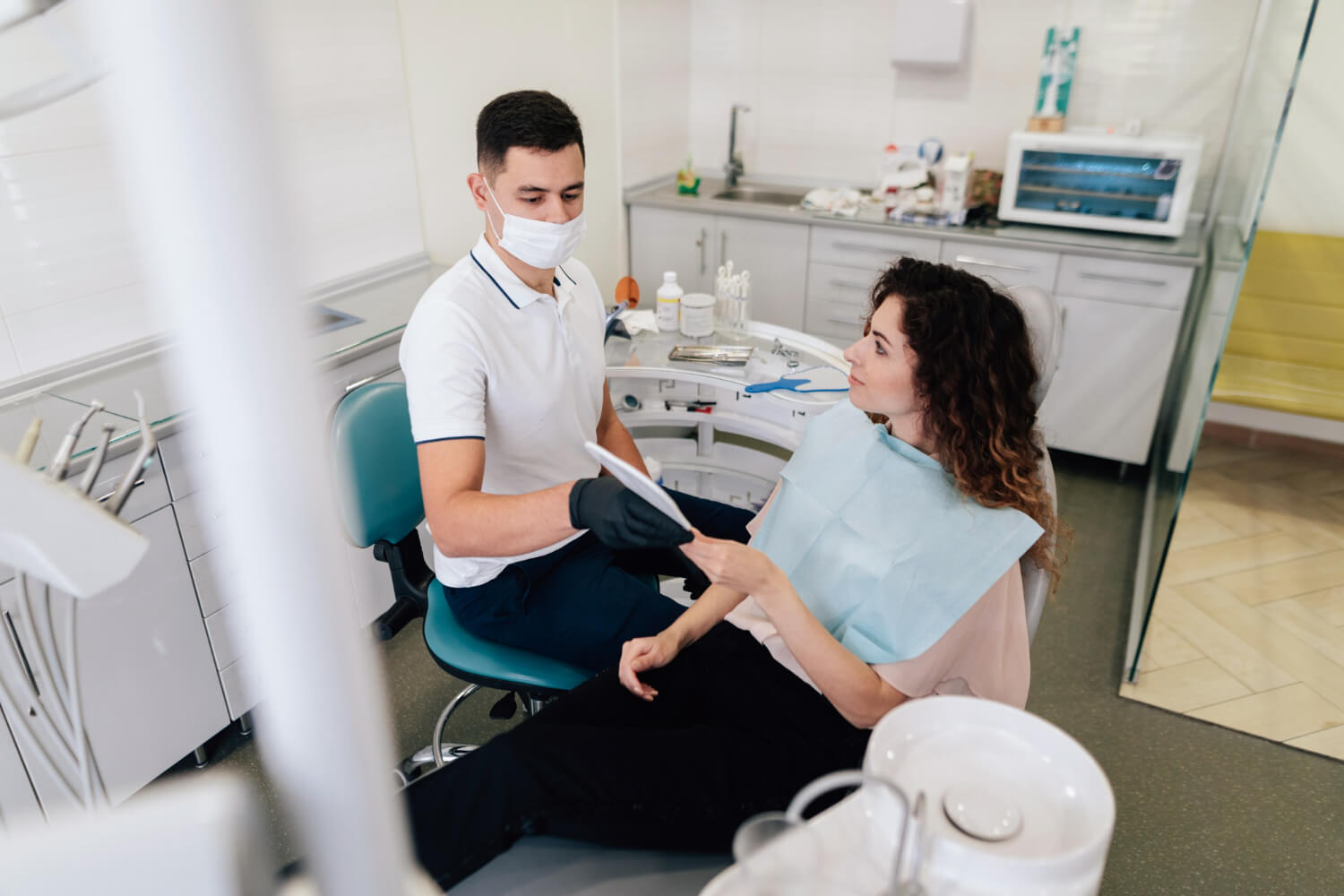 Dentista mostra espelho para paciente na cadeira odontológica durante consulta de tratamento de canal na So Riso em Patos de Minas.