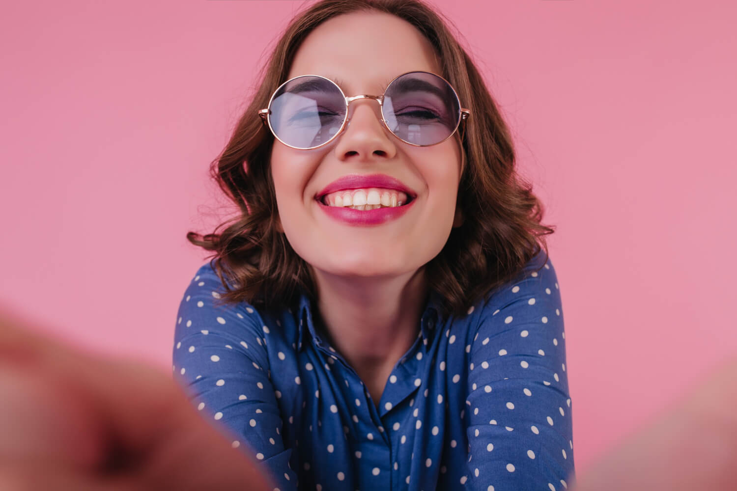 Mulher sorridente de óculos escuros exibe dentes brancos após clareamento dental em Patos de Minas - MG na Só Riso.